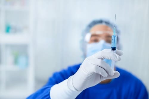 врач готовит шприц к инъекции